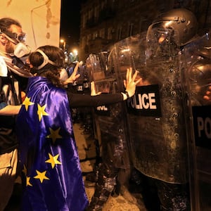 Demonstrators stand in front of police officers with riot gear.