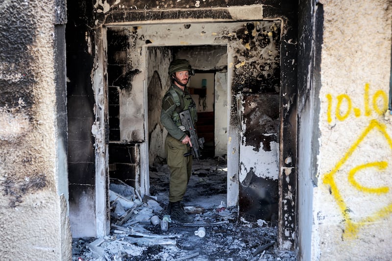 An Israeli soldier stands inside of a burnt building in Kfar Aza in southern Israel near the Gaza Strip