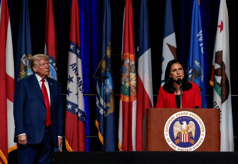 Donald Trump stands on stage while Tulsi Gabbard speaks into a microphone.