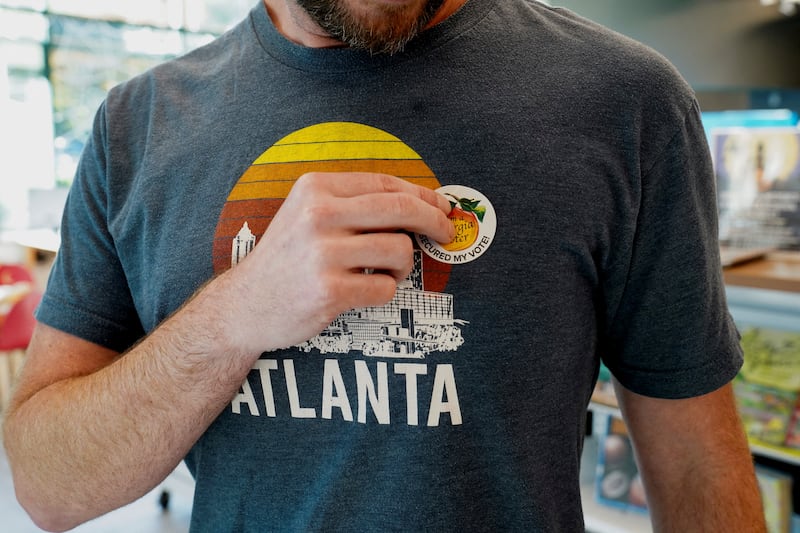 A voter puts on their sticker after voting as Georgians turned out a day after the battleground state opened early voting, in Atlanta, Georgia, U.S., October 16, 2024.