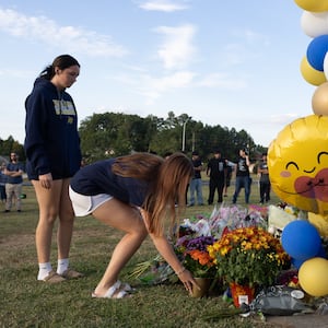 Two students place flowers at a memorial outside of Apalachee High School