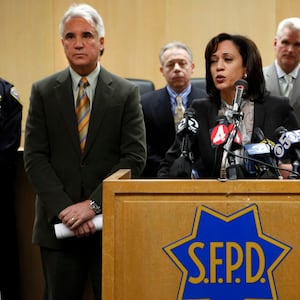 Kamala Harris in front of a S.F.P.D branded lectern with a police officer behind her