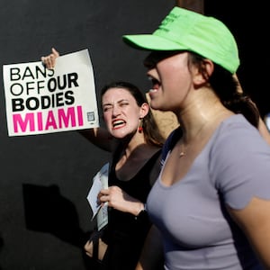 Protesters chant wild holding a sign that says, “Bans off our bodies Miami.”