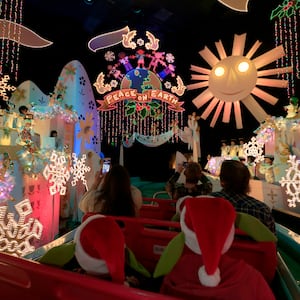 Guests take a boat ride through \"It's a Small World\" ride decorated for the holiday season during the Star Wars Season of The Force at Disneyland