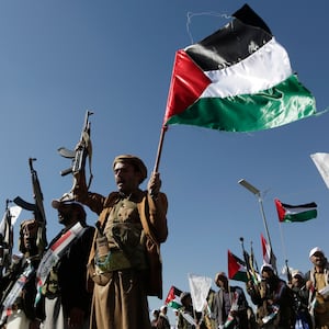 Yemenis recently militarily trained by the Houthi movement holding up their guns and Palestinian flag chant slogans