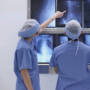 three doctors in scrubs looking at four x-rays acute flaccid myelitis afm cdc centers for disease control rare paralysis polio like mystery