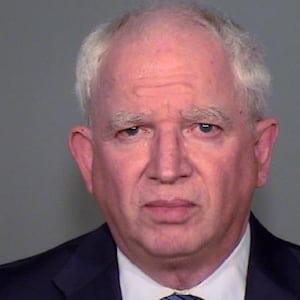 John Eastman stares forward in a mugshot, wearing a suit and tie.