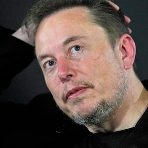 A close up of Elon Musk with his hand on his head