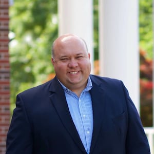 Bubba Copeland, wearing a button-up shirt and blazer, smiles in a headshot.