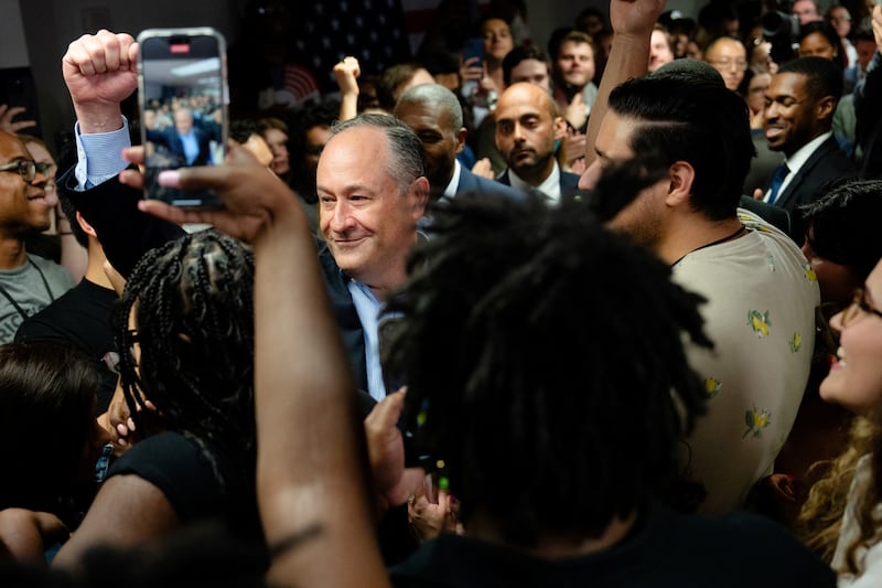 Doug Emhoff pumping his fist surrounded by people taking photos with phones