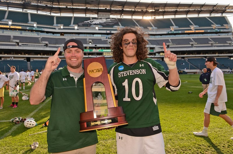 Greg Furshman and Callum Robinson pose with a trophy on a field 