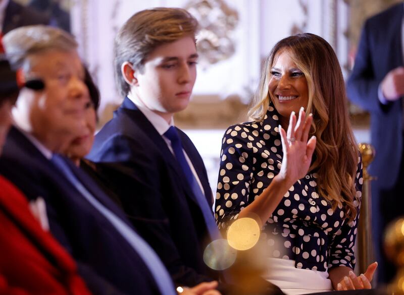 Melania Trump smiling and waving beside Barron