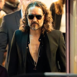 Russell Brand wears sunglasses as he walks out of a theatre in London.