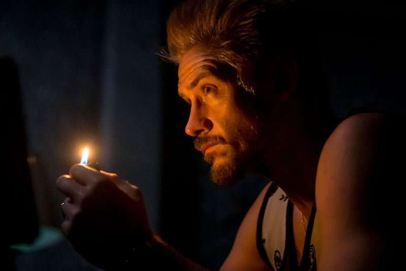 A still from 'Justified: City Primeval' of Boyd Holbrook holding a match near his face in the dark 