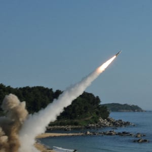 A missile launching over a shoreline.