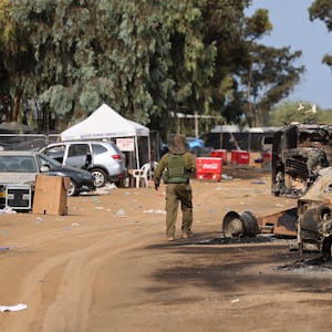 An Israeli soldier walks past burned vehicles at the site of the weekend attack on the Supernova desert music festival by Palestinian militants near Kibbutz Reim.