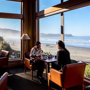 Guests sit in a restaurant at Long Beach Lodge overlooking the beach in Tofino, Canada.