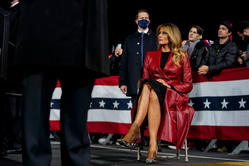 Melania Trump sits in a chair at a rally. 