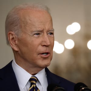 President Joe Biden talks to reporters with chandelier in the background.