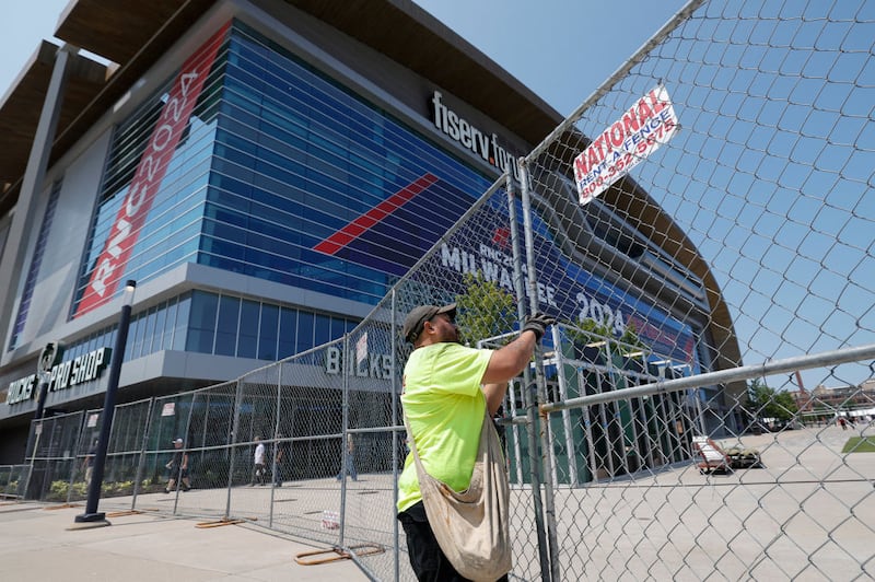 A security worker helps put up a fence outside Fiserv Forum, where the RNC begins Monday.