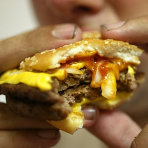 A close-up photo of a man’s hands holding a Big Mac, about to take a bite.