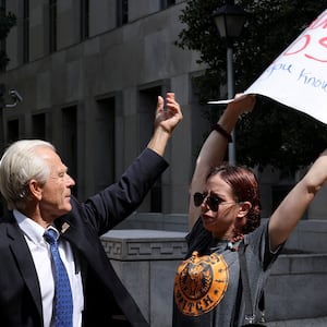 Peter Navarro, a White House economic adviser under former U.S. President Donald Trump, tries to grab a protestors sign while speaking to reporters