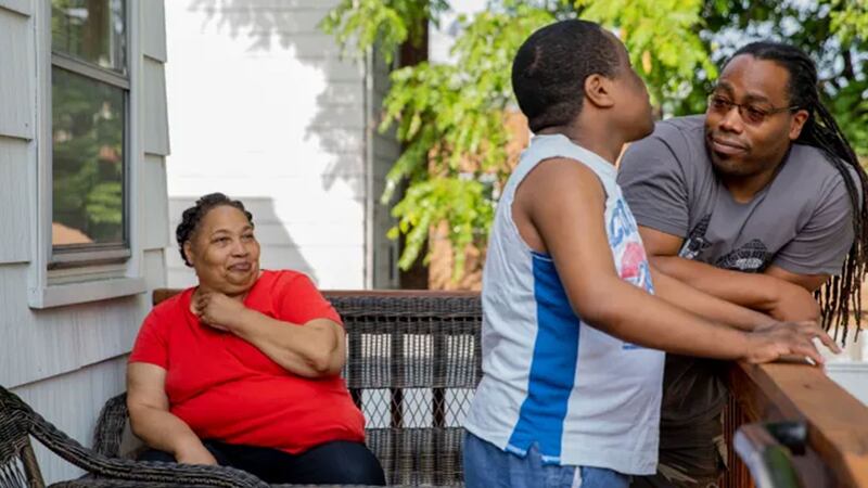 Daisy, Derrick, and John Johnson stand on a porch in ‘Tell Them You Love Me’