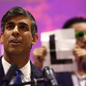 Independent candidate Niko Omilana holds an "L" behind Britain's Prime Minister and Conservative Party leader Rishi Sunak as he delivers a speech after retaining his seat as MP for Richmond and Northallerton in Northallerton, early on July 5, 2024. 