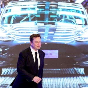 Elon Musk in front of a picture of a Tesla Model 3