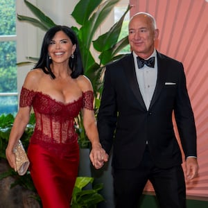 Amazon CEO Jeff Bezos (wearing a tuxedo) and Lauren Sanchez (wearing a scarlet red lace and silk gown) arrive for a State Dinner honoring Japan's Prime Minister at the White House.