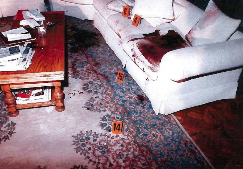 A crime scene photo shows bloodstains on a white sofa and floor rug in the Menendez family home's den, where brothers Lyle and Erik Menendez fatally shot their parents in August 1989.