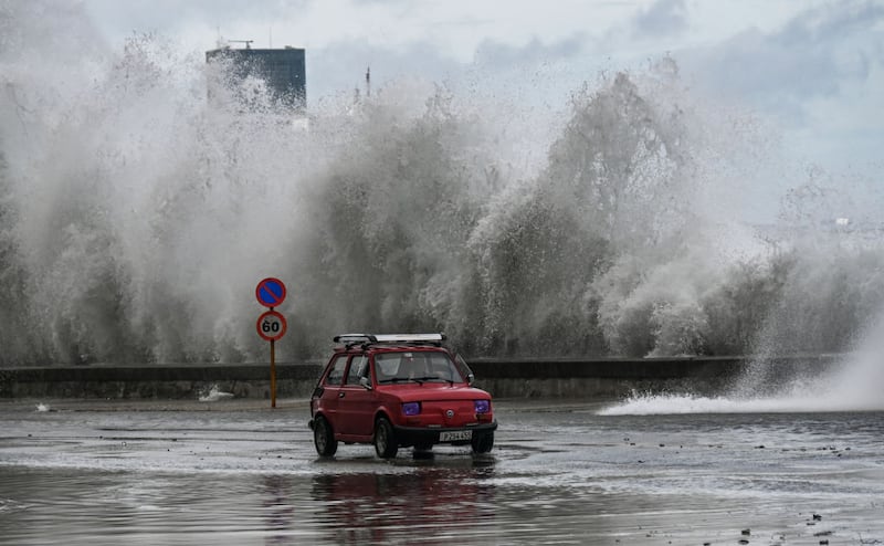 A car drives past waves just ahead of Hurricane Milton’s landfall.