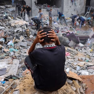 A child reacts as people salvage belongings amid the rubble of a damaged building following Israeli strikes on Rafah in southern Gaza, on Nov. 12, 2023.