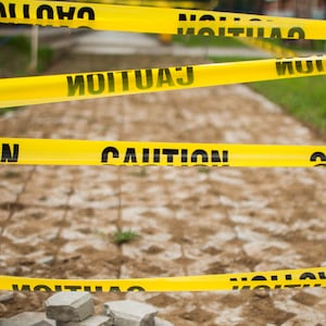 A close-up view of yellow tape caution sign outdoor during day time.