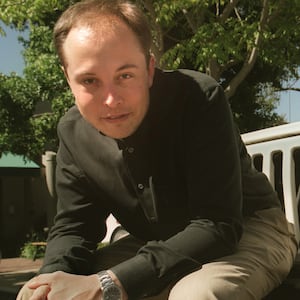 Elon Musk with less hair sitting on the fender of a white Jeep Wrangler