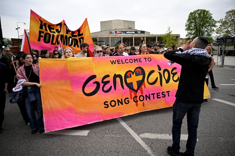 Protesters march carrying sign that says "Welcome to Genocide Song Contest"