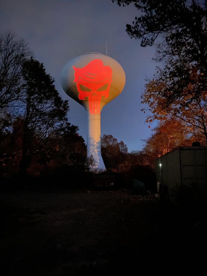 A Punisher skull logo with Donald Trump-like hair is projected in red onto the town water tower in Hanson, MA.