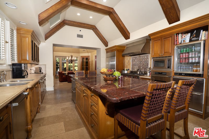 Wooden cabinetry and paneling, as well as a marble breakfast bar, in the home's kitchen.