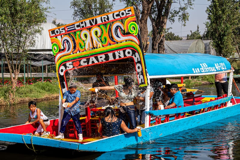 Photograph of people having a water fight on a colorful boat.