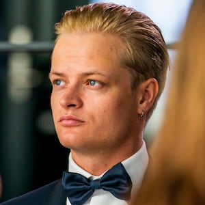 Marius Borg Høiby, wearing a suit and tie, sits at a table during an event.