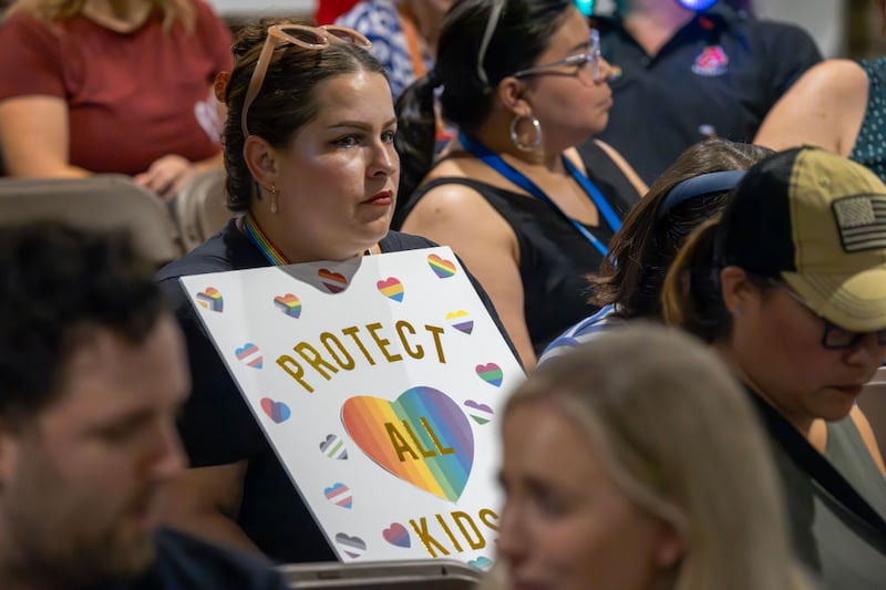 A person holds a sign in opposition to a policy that the Chino Valley school board passed in July that requires schools to notify parents if their child comes out as transgender.