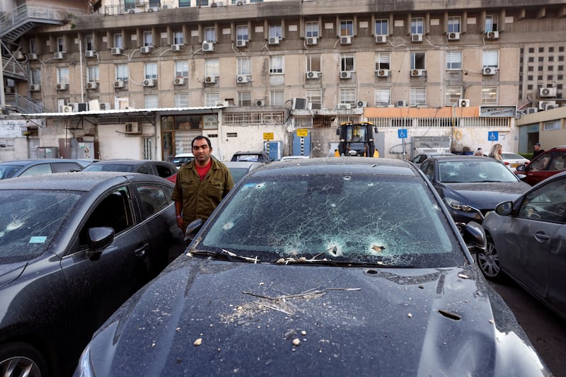 An Israeli soldier stands among cars damaged by rockets in Israel.