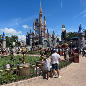 People walk in front of the castle at Walt Disney World.