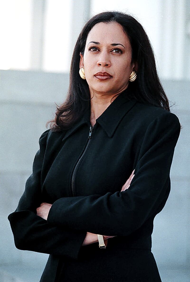 A young Kamala Harris in black suit with arms folded