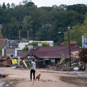 A woman walks her dog on a destroyed street in Asheville, North Carolina.