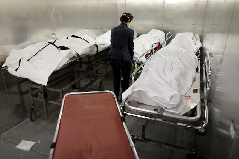 A woman in a morgue in front of two gurneys draped in white sheets