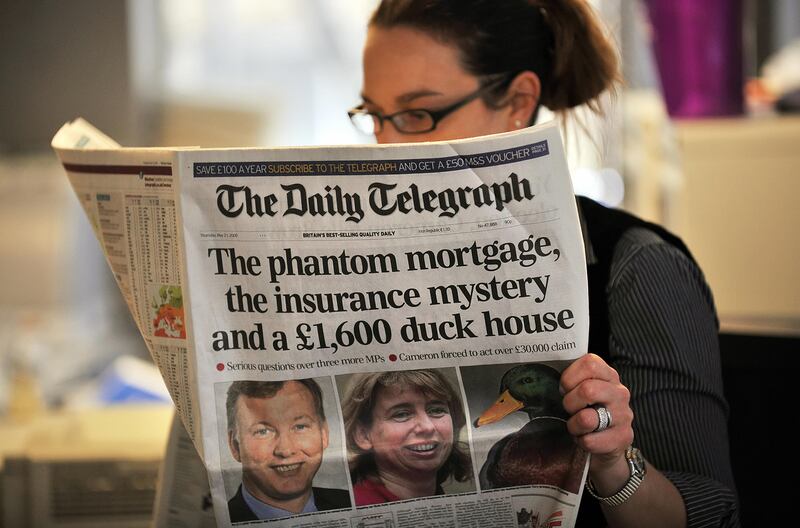 A woman reads a copy of the Daily Telegraph newspaper in London.