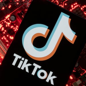 A smartphone with a displayed TikTok logo is placed on a computer motherboard.