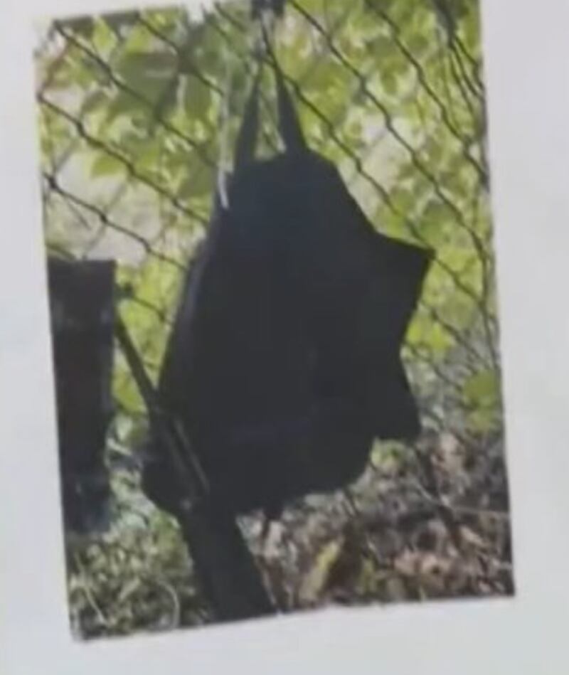 A backpack leaning against a fence.