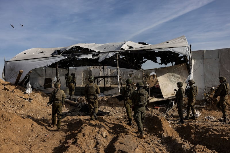 A photo shows the backs of IDF soldiers going into a torn tent camp in Gaza.